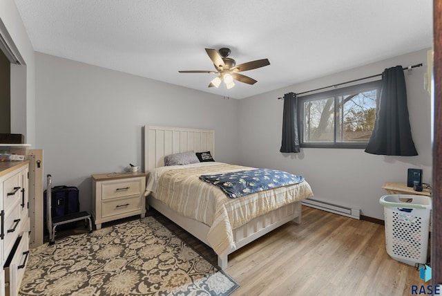 bedroom with baseboards, ceiling fan, a baseboard heating unit, and light wood finished floors