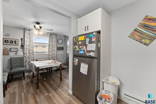 110 N Kimball St, Canton, SD 57013 - interior space with white cabinetry, a baseboard heating unit, freestanding refrigerator, wood finished floors, and a ceiling fan