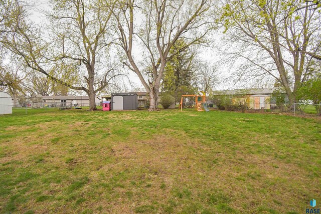 view of yard with a playground, an outbuilding, a fenced backyard, and a storage shed