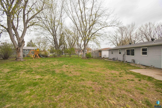 view of yard with a playground, fence, and central air condition unit