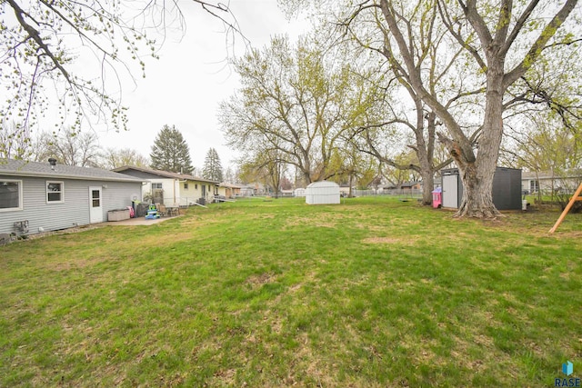 view of yard with an outdoor structure, a patio area, a shed, and fence