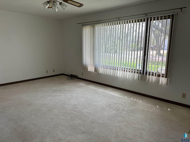 carpeted empty room with plenty of natural light, baseboards, and ceiling fan