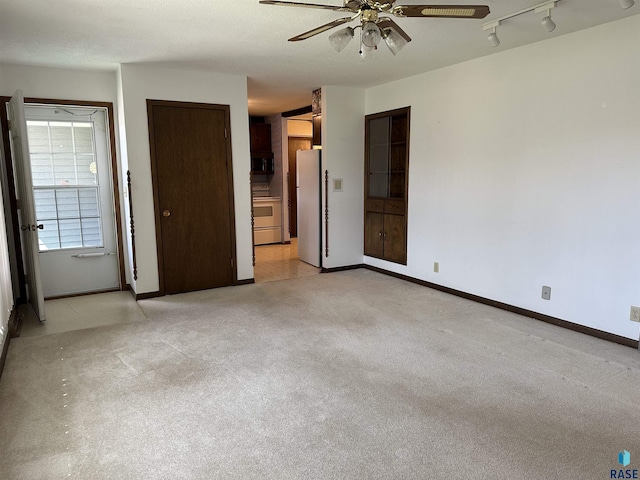 interior space with baseboards, freestanding refrigerator, connected bathroom, and light colored carpet