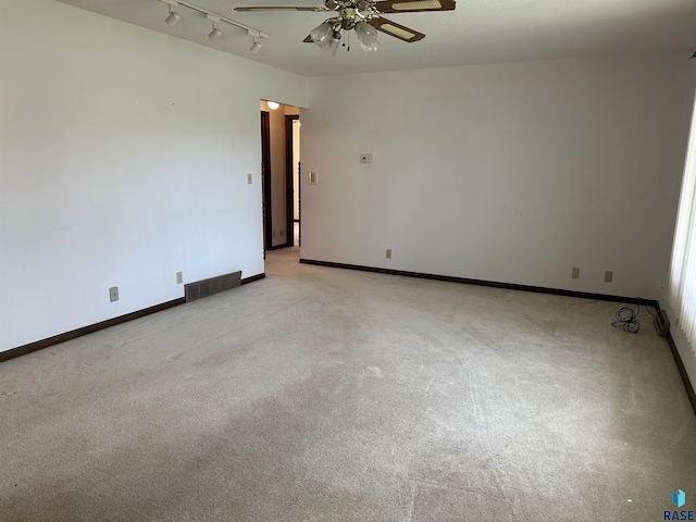 spare room featuring a ceiling fan, light colored carpet, visible vents, and track lighting