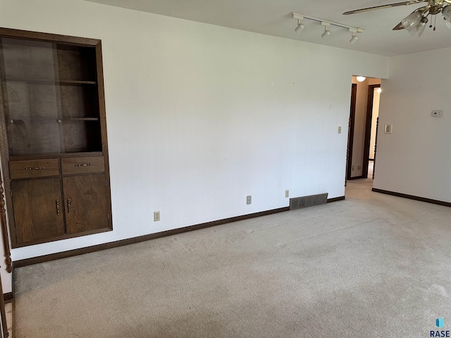 unfurnished room featuring baseboards, visible vents, a ceiling fan, and light colored carpet