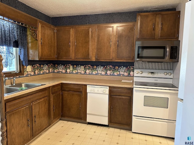 kitchen with a sink, light countertops, white appliances, and light floors