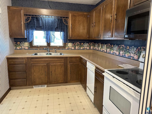 kitchen with visible vents, white appliances, light floors, light countertops, and a sink