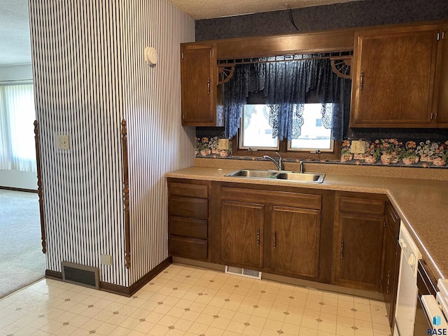 kitchen with visible vents, a sink, wallpapered walls, and light countertops
