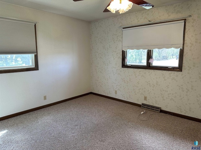 carpeted spare room featuring ceiling fan and visible vents
