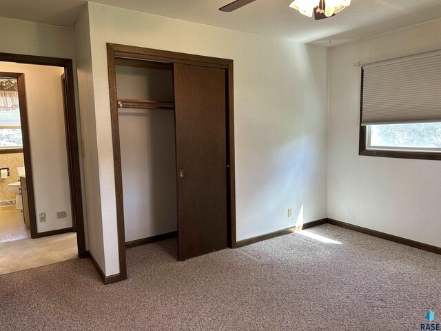 unfurnished bedroom featuring baseboards, light colored carpet, and a closet