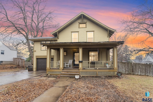 view of front of home featuring a garage, fence, covered porch, and driveway