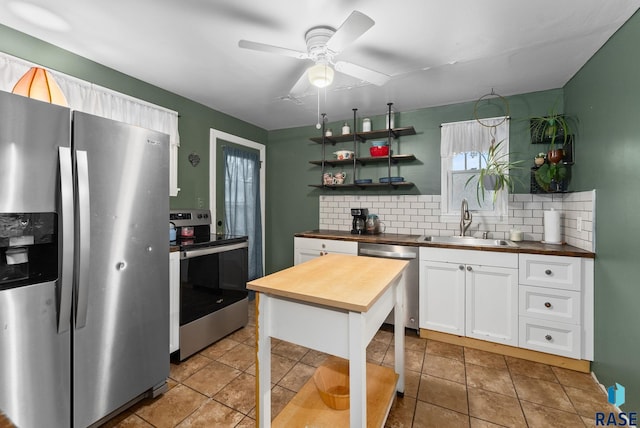 kitchen with decorative backsplash, wooden counters, appliances with stainless steel finishes, a sink, and white cabinets