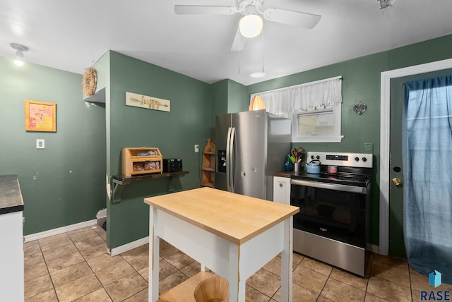 kitchen featuring baseboards, a ceiling fan, light tile patterned floors, and stainless steel appliances