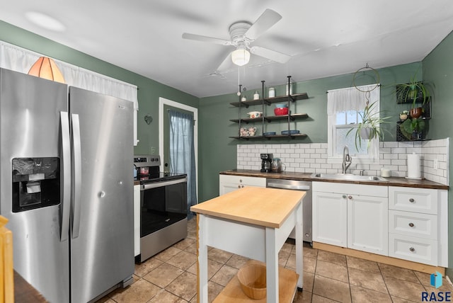 kitchen featuring white cabinets, tasteful backsplash, a sink, wood counters, and appliances with stainless steel finishes