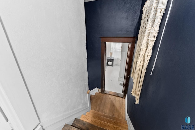 staircase with baseboards and wood finished floors