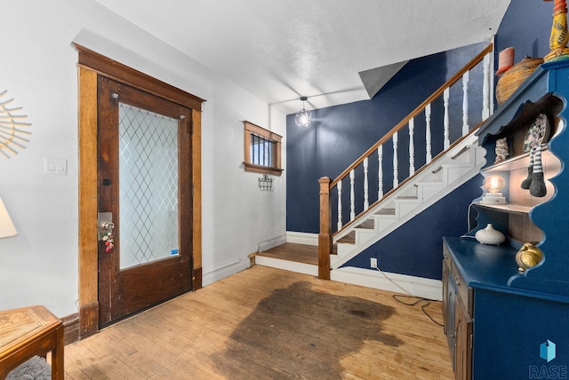 foyer entrance featuring stairway, baseboards, and wood finished floors