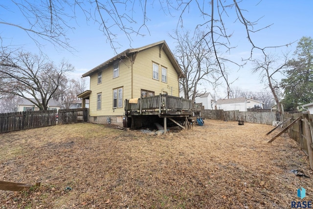rear view of property featuring a fenced backyard and a wooden deck