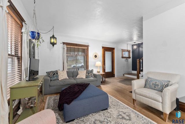 living room featuring baseboards, wood finished floors, and stairway