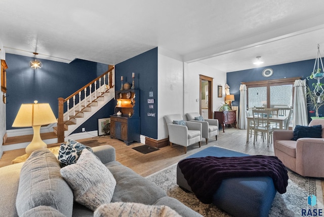 living room featuring stairs, baseboards, and wood finished floors