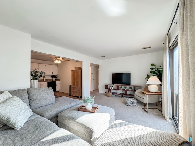 living room with a ceiling fan, visible vents, and light carpet