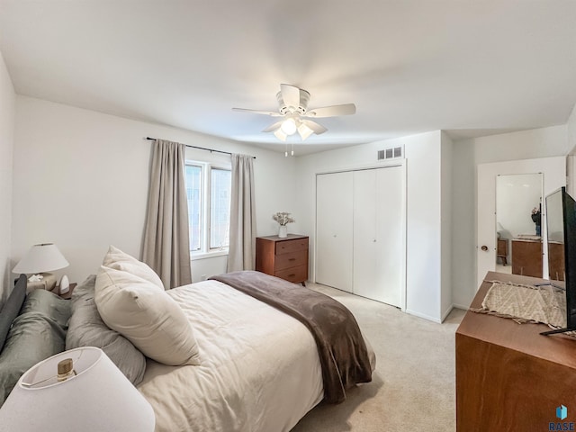 bedroom with a ceiling fan, visible vents, baseboards, a closet, and light carpet