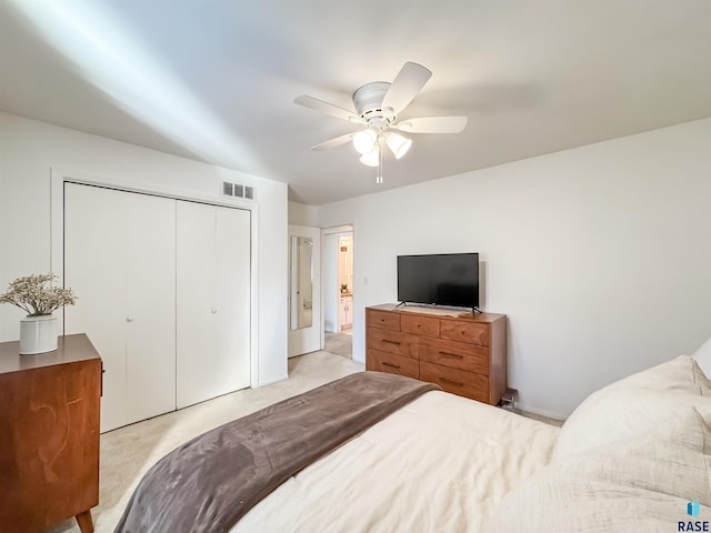 bedroom with a ceiling fan, visible vents, light carpet, and a closet