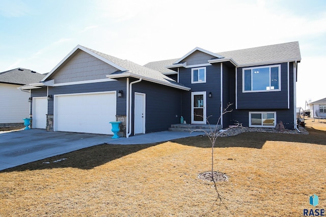 split level home featuring a front yard, a shingled roof, driveway, and a garage