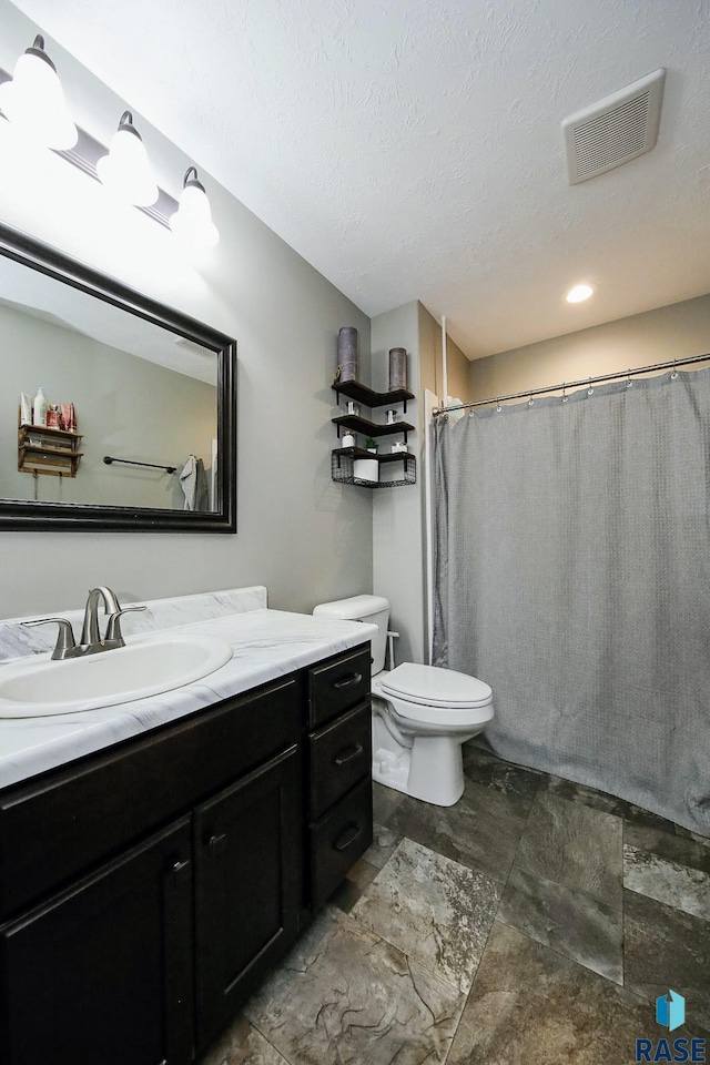 full bathroom featuring vanity, toilet, a textured ceiling, and visible vents