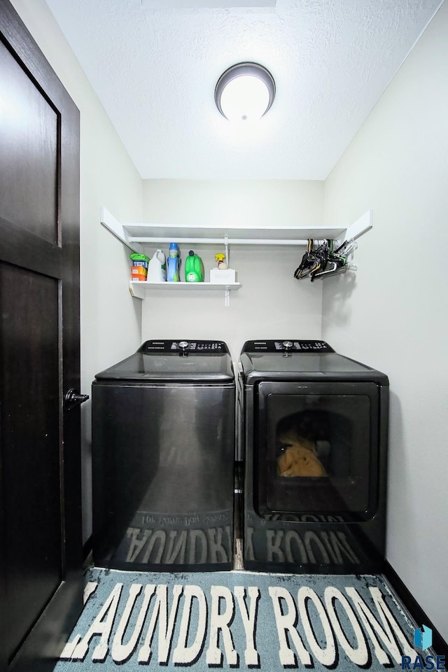clothes washing area with washing machine and clothes dryer, laundry area, and a textured ceiling