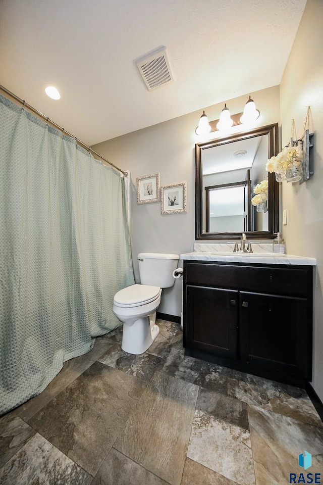 bathroom featuring stone finish floor, toilet, visible vents, a shower with shower curtain, and vanity