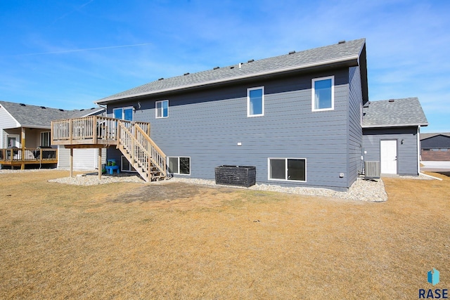 rear view of property featuring a deck, a yard, stairway, central AC unit, and a shingled roof
