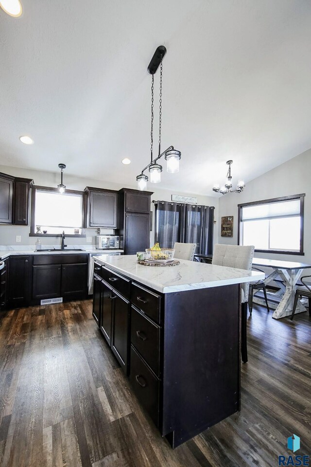 kitchen featuring hanging light fixtures, a sink, a chandelier, dark wood finished floors, and a kitchen island