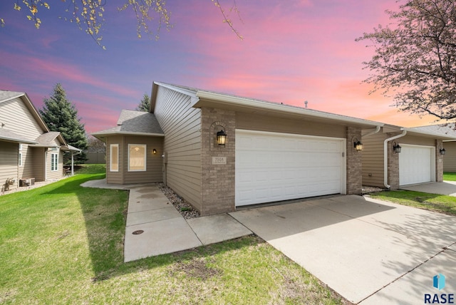 view of front of house featuring a garage, concrete driveway, a lawn, and brick siding