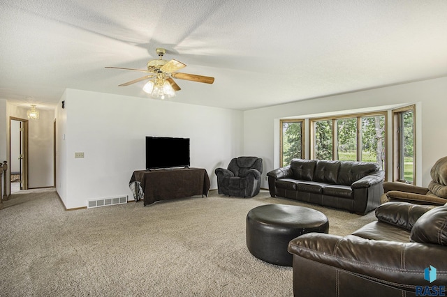 carpeted living room with visible vents, baseboards, and ceiling fan