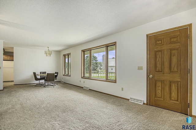 unfurnished room featuring visible vents, an inviting chandelier, and carpet