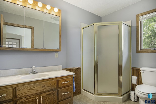 bathroom with vanity, a wainscoted wall, a stall shower, and toilet