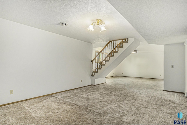 unfurnished living room with a textured ceiling, carpet, and stairway