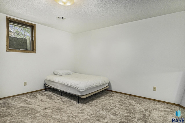 carpeted bedroom featuring a textured ceiling, baseboards, and visible vents