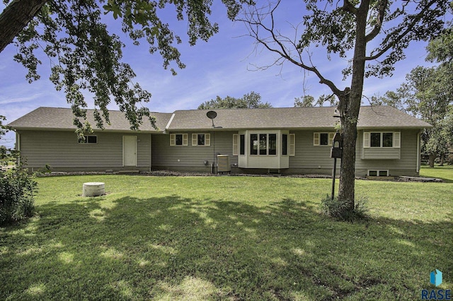 rear view of house with central AC unit and a yard