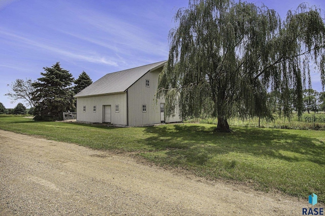 view of side of property featuring an outbuilding, a yard, and metal roof
