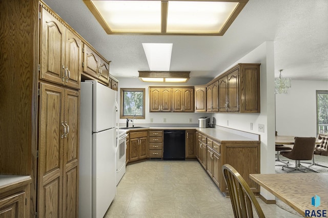 kitchen with a sink, light floors, a healthy amount of sunlight, and white appliances