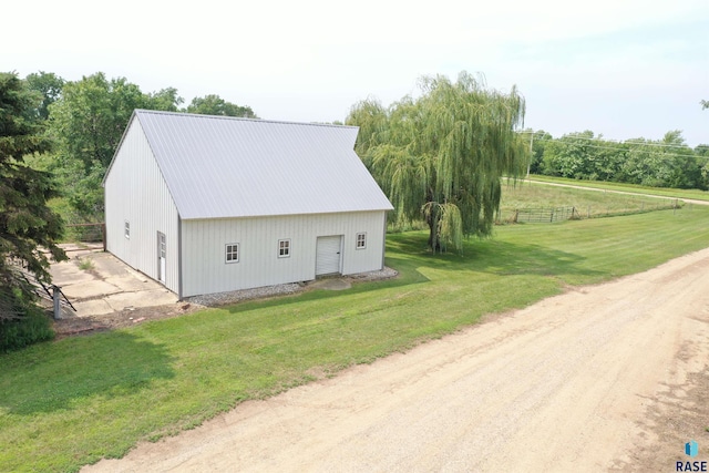 exterior space featuring an outdoor structure, fence, a yard, metal roof, and an outbuilding