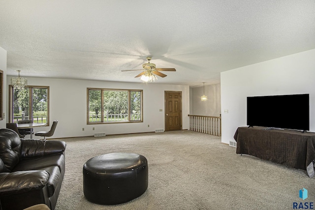 living area featuring carpet floors, ceiling fan with notable chandelier, a textured ceiling, and a wealth of natural light