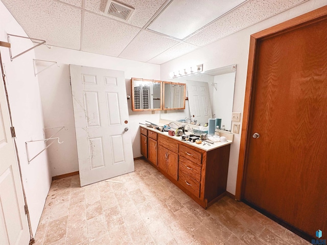 120 SW 2nd St Unit 1 & 2, Wentworth, SD 57075 - bathroom featuring double vanity, baseboards, visible vents, and a paneled ceiling