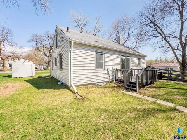 409 Boxelder St, Valley Springs, SD 57068 - rear view of house with a lawn, a wooden deck, a chimney, and an outbuilding