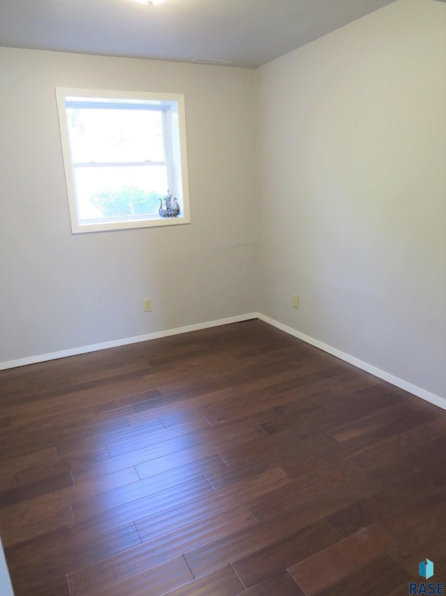 unfurnished room with baseboards and dark wood-type flooring