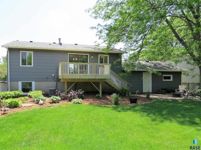 back of property with a lawn, a wooden deck, and stairs