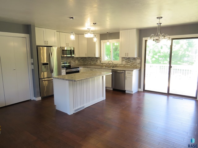 kitchen with a sink, backsplash, stainless steel appliances, and white cabinetry