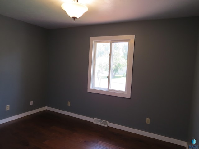 spare room with dark wood-style flooring, baseboards, and visible vents