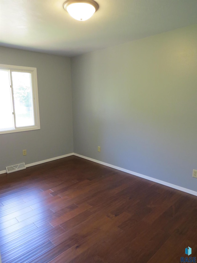 unfurnished room with visible vents, baseboards, and dark wood-type flooring